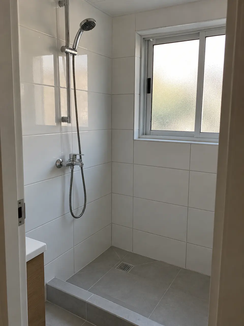 Imagen referencial de baño renovado con cerámica blanca y ducha